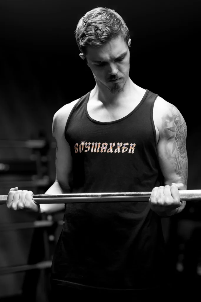 SOYMAXXER CURL Bearded man in gym lifting a heavy dumbbell, showcasing strength and fitness.