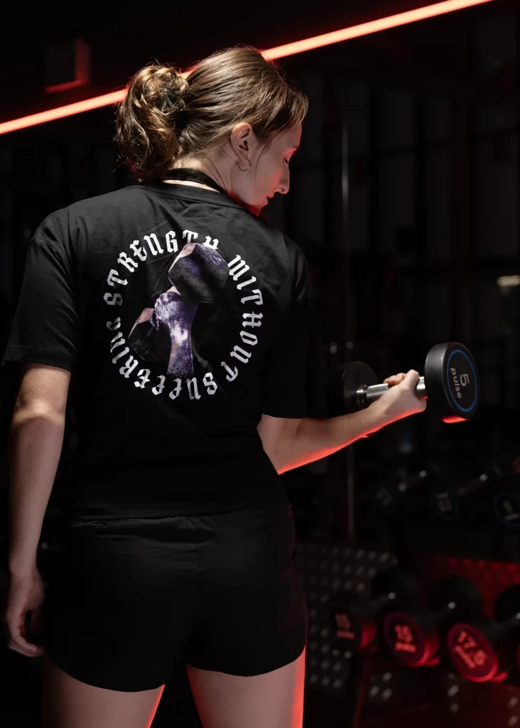 Lady in gym holding a dumbell wearing a plantbeast gym tshirt